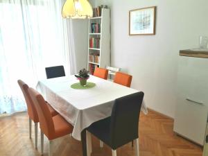 uma mesa de jantar com uma toalha de mesa branca e cadeiras laranja em Apartments Ogrin em Portorož