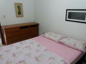 a bedroom with a bed with pink sheets and a dresser at Apartamento em Cabo Frio in Cabo Frio