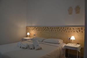 una camera da letto con un grande letto bianco con due tavoli di La Giara a Torre Lapillo