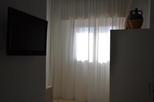 a window with a white curtain and a television at La Giara in Torre Lapillo