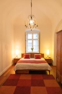 a bedroom with a bed with a window and a chandelier at Design Apartment Eger in Eger