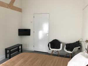 a bedroom with two chairs and a tv on a wall at Bij Zelle in Garderen