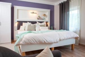 a bedroom with a large white bed with purple walls at Landhotel Rosenschänke in Kreischa