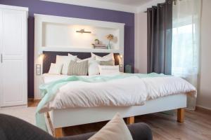 ein Schlafzimmer mit einem großen weißen Bett mit lila Wänden in der Unterkunft Landhotel Rosenschänke in Kreischa