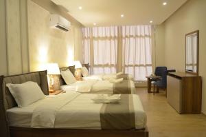 une chambre d'hôtel avec deux lits et une télévision dans l'établissement Larissa Suites, à Khobar 68 autres photos