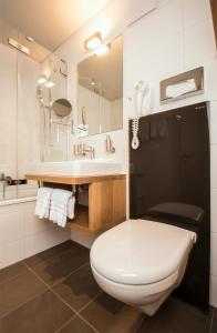 a bathroom with a white toilet and a sink at Hotel National in Frutigen