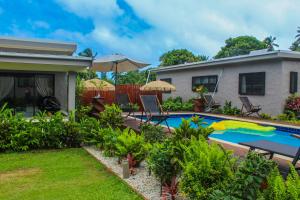 Cook Islands Holiday Villas-Tuoro Holiday في راروتونغا: حديقه خلفيه بها مسبح ومنزل