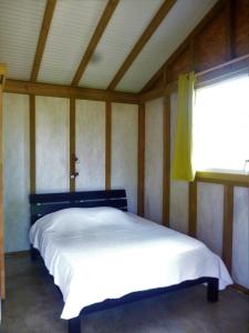 um quarto com uma cama branca num quarto com uma janela em Karukera em Saint-François