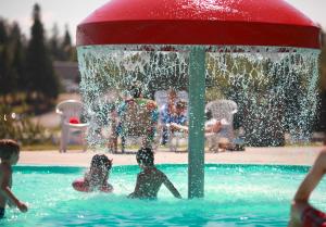 a group of children playing in a fountain in a pool at Centre de Villégiature Dam-en-Terre in Alma