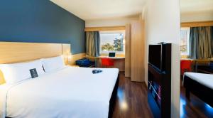 a hotel room with a bed and a tv at ibis Paulinia in Paulínia