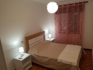 a bedroom with a bed and two night stands with lamps at Apartamento Fuseta in Fuzeta