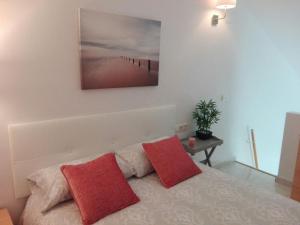 ein Schlafzimmer mit einem Bett mit zwei roten Kissen in der Unterkunft Cozy Loft Torremolinos in Torremolinos + 22 Fotos