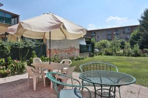 una mesa, sillas y una sombrilla en el patio en Affittacamere La Rosa, en Lucca