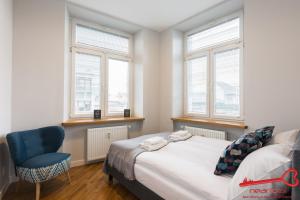 Schlafzimmer mit einem Bett, einem blauen Stuhl und Fenstern in der Unterkunft Luxury Apartments Nearto Main Square in Krakau