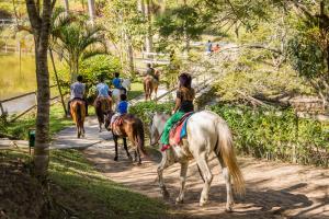 un grupo de personas montando caballos por un camino en Hotel Fazendão en Santa Branca