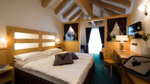 una camera con un grande letto in una stanza con una scrivania di Hotel Chalet Sas Morin a Pozza di Fassa