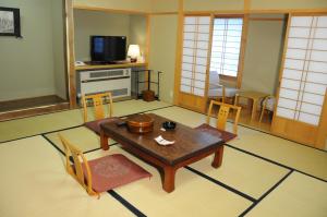 a living room with a table and chairs and a television at Onsen Yupopo in Senboku