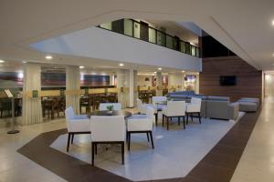 un restaurante con sillas y mesas blancas en un edificio en Ritz Suites Home Service en Maceió