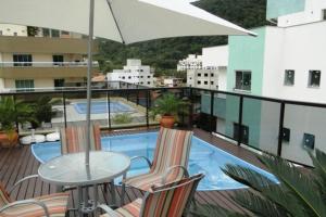 balcón con mesa, sillas y piscina en Excelente apto 3 dormitorios com piscina exclusiva, en Bombinhas