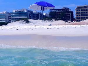 una playa con una sombrilla en la arena y el agua en Apartamento Luxo em Arraial do Cabo- RJ, en Arraial do Cabo