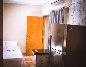 a small room with a bed and a refrigerator at Solar Maresias Flats in Maresias
