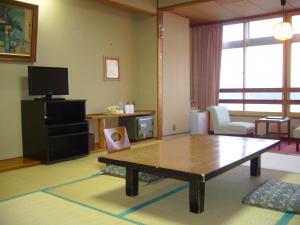 a living room with a coffee table and a tv at Aokiya in Sado