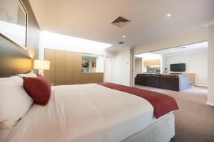 um quarto com uma grande cama branca e uma televisão em Ramada Hotel & Suites by Wyndham Cabramatta em Cabramatta