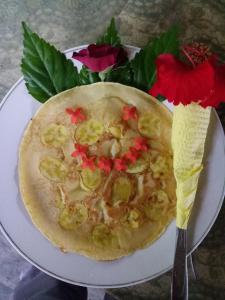 a pizza on a plate with flowers and a fork at Green Lodge Tangkahan in Tangkahan