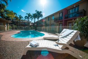 uma piscina com uma chaise longue ao lado de um edifício em Ramada Hotel & Suites by Wyndham Cabramatta em Cabramatta