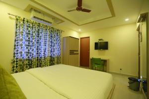 um quarto com uma cama branca e uma janela em Kans One em Chennai