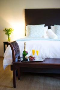 een bed met een tafel met een fles wijn en drankjes bij The Graaff-Reinet Suites in Graaff-Reinet