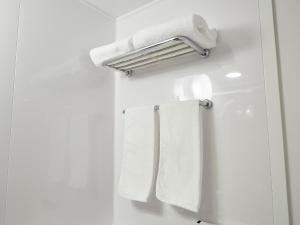 bagno con asciugamani bianchi appesi a un appendiabiti di Hearton Hotel Shinsaibashi Nagahoridouri ad Osaka