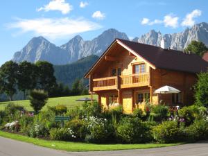 a wooden house with mountains in the background at Blockhaus Royer in Ramsau am Dachstein