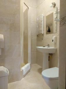 a white bathroom with a sink and a toilet at Aparthotel NA DOBU in Lviv