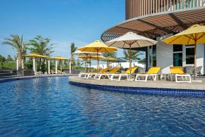 a swimming pool with yellow chairs and umbrellas at Oceanami Villas & Beach Club - Managed by Thang Long Group in Long Hai