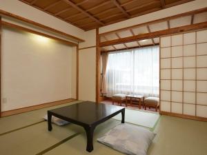 a room with a table and a large window at Riverside Uedakan in Chikuma