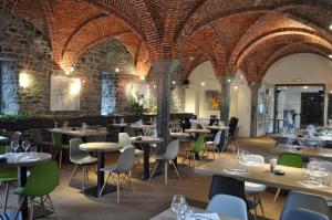 a restaurant with tables and chairs and a brick wall at Golf & Hôtel de Falnuée in Mazy