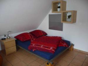 a bed with red pillows in a room at 4_Zimmer_Ferienwohnung in Wathlingen +5 photos