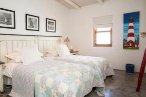 two beds in a bedroom with a lighthouse on the wall at Sugar Shack in Paternoster