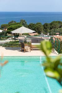 a swimming pool with chairs and a table and umbrella at Résidence Costa d'Oru in Saint-Florent