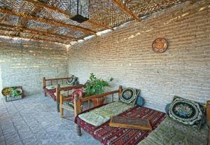 Habitación con bancos y pared de ladrillo. en Amulet Hotel, en Bukhara
