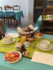 une table avec des assiettes de nourriture et une corbeille de fruits dans l'établissement Logis Hotel du Midi, à Salon-de-Provence