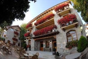 un bâtiment avec des fleurs rouges sur son côté dans l'établissement Nava Real, à Navacerrada