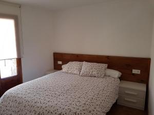 een slaapkamer met een bed met een houten hoofdeinde bij Cal Sastre in Castellar de NʼHug