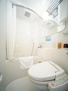 a white bathroom with a toilet and a bath tub at Super Hotel Hiroshima in Hiroshima