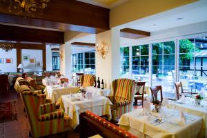 ein Restaurant mit weißen Tischen, Stühlen und Fenstern in der Unterkunft Romantik SPA Hotel Seefischer in Döbriach