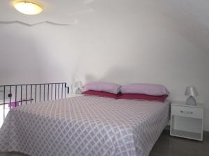 a white bedroom with a bed with pink pillows at Le Case dei Pescatori - Coccinella Rossa in Ponza