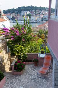 un banco sentado en un balcón con flores en Apartman Dragica en Mali Lošinj
