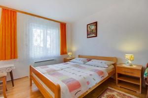 um quarto com uma cama e uma janela com cortinas laranja em Apartman Dragica em Mali Lošinj