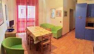 リド・ディ・イエゾロにあるCondominio Romeoのテーブルと緑の椅子が備わるお部屋